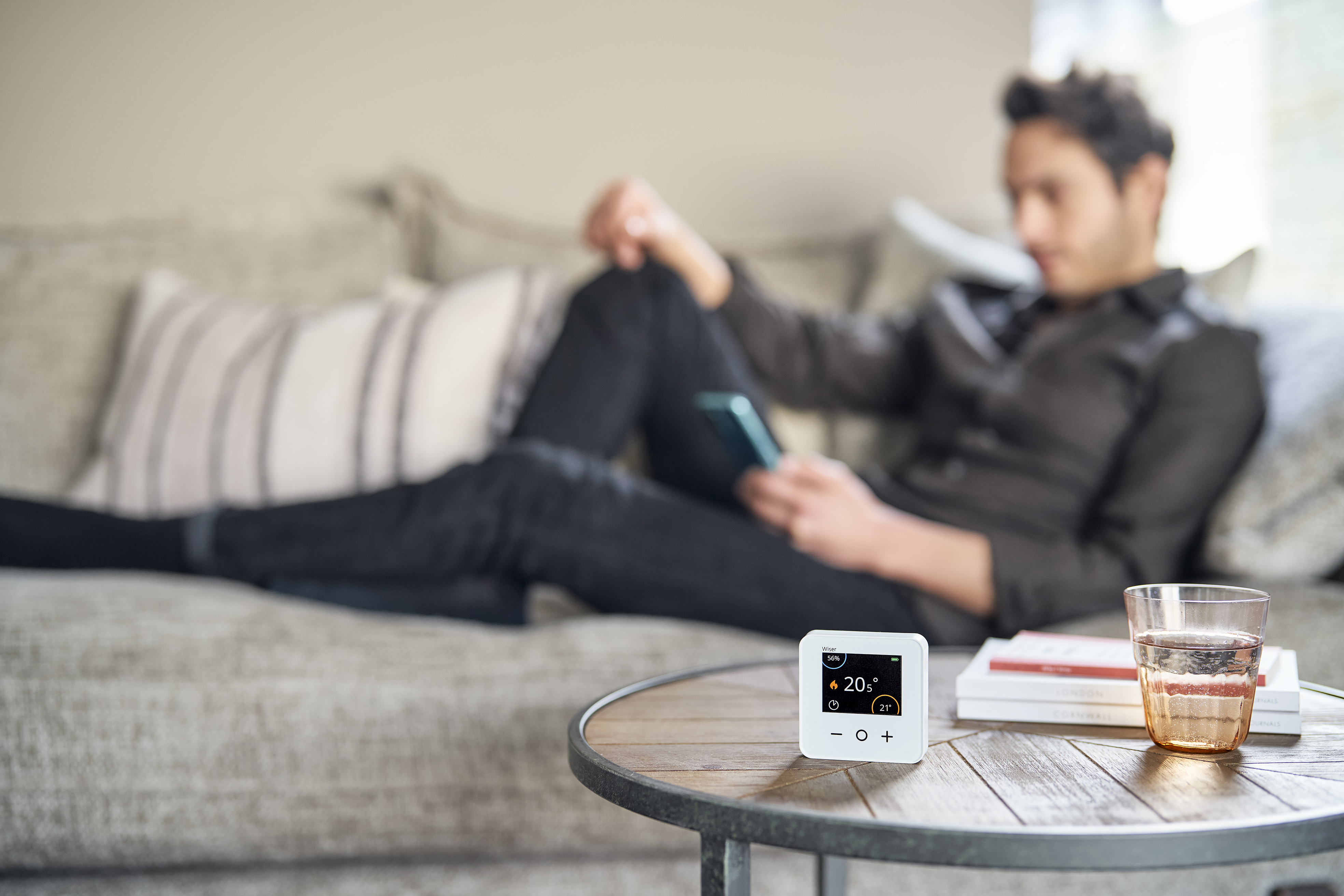 Man lounging on sofa in comfort while a Wiser smart thermostat creates a warm environment in Comfort Mode