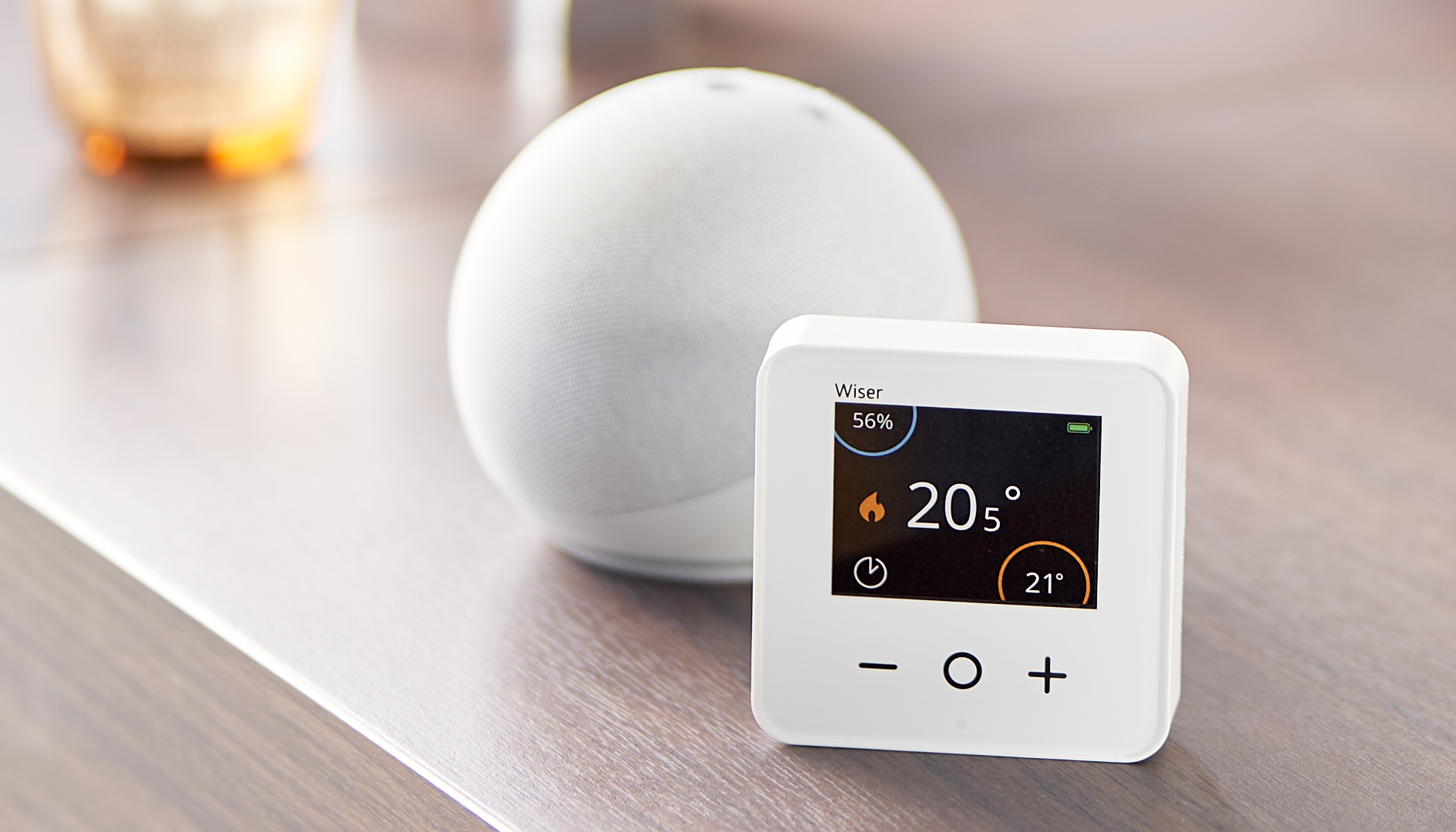 Wiser's smart room thermostat next to an Amazon Alexa Dot - Smart heating systems by Wiser are compatibel with Alexa and Google Assistant voice controls